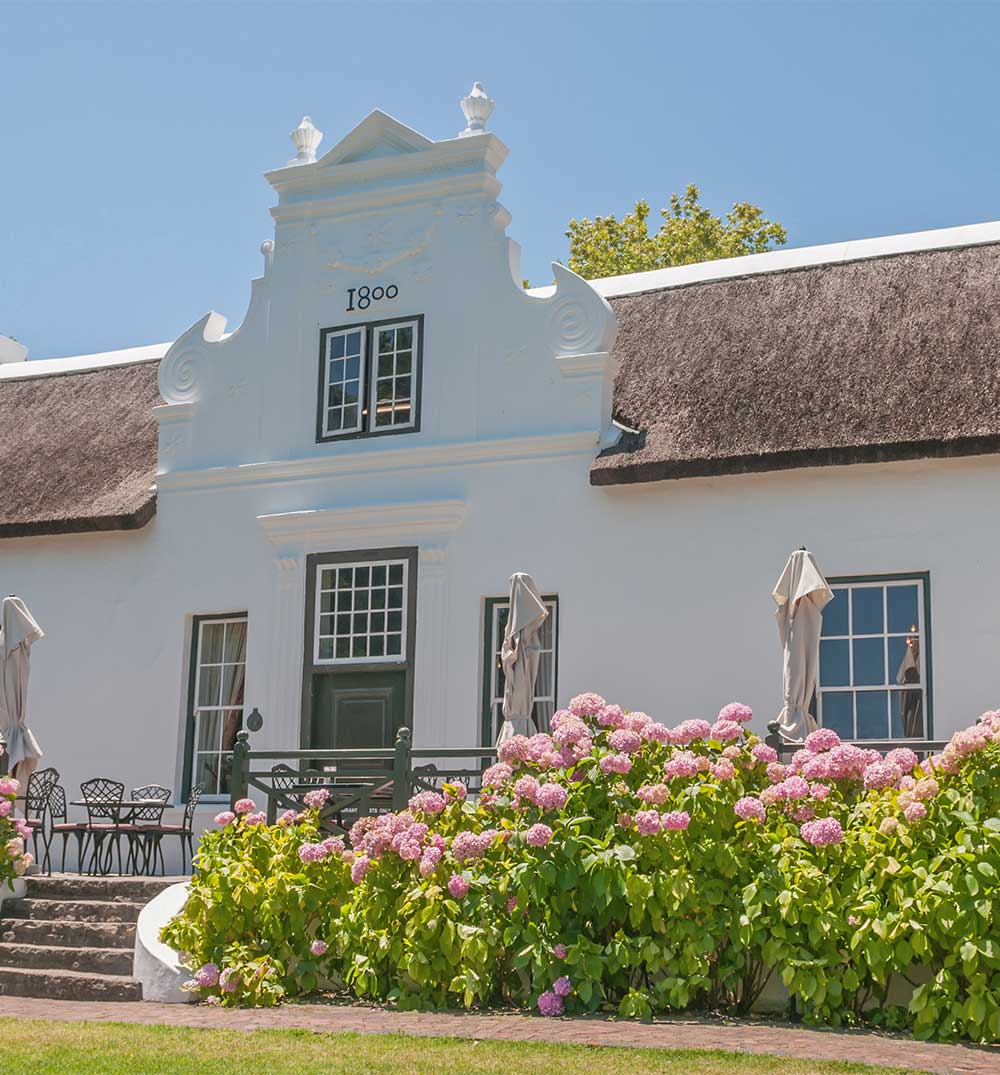 Historic Cape Dutch-style building in Bellville with a thatched roof and garden. Cleaning Services in Bellville.